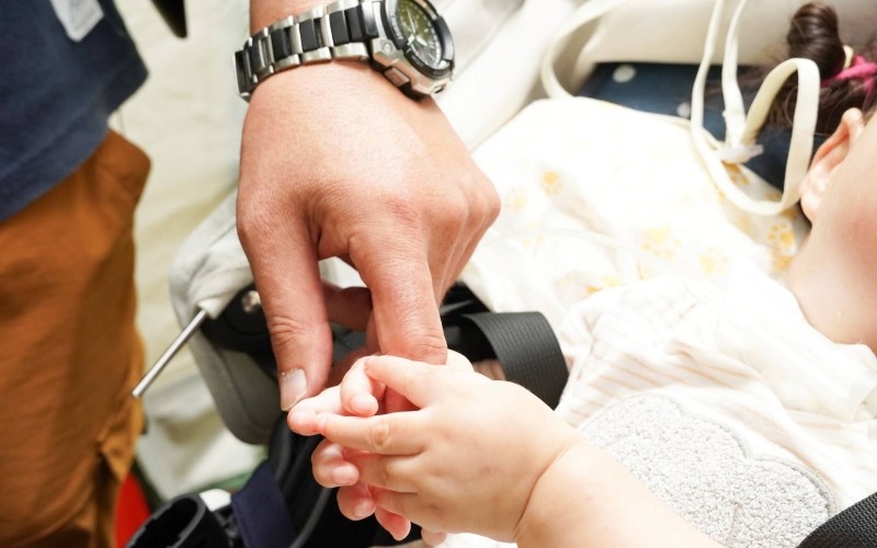 ボランティアさんの指を握る小さな手の画像